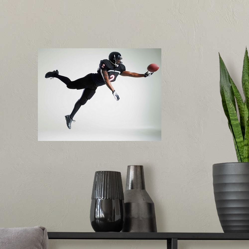 A modern room featuring Football player leaping in mid air to catch ball