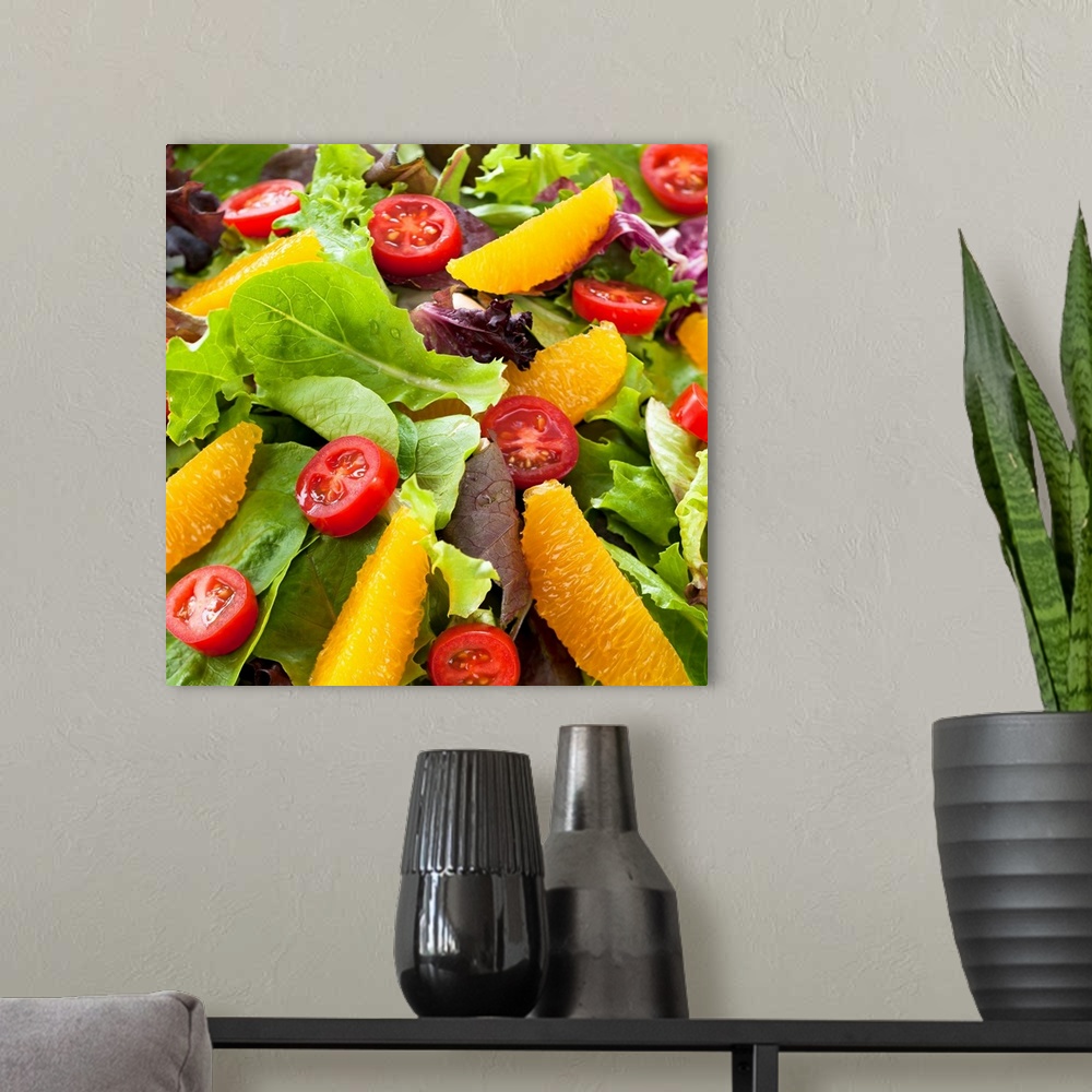 A modern room featuring Square photo art of oranges and tomatoes sitting on top of a bed of lettuce.