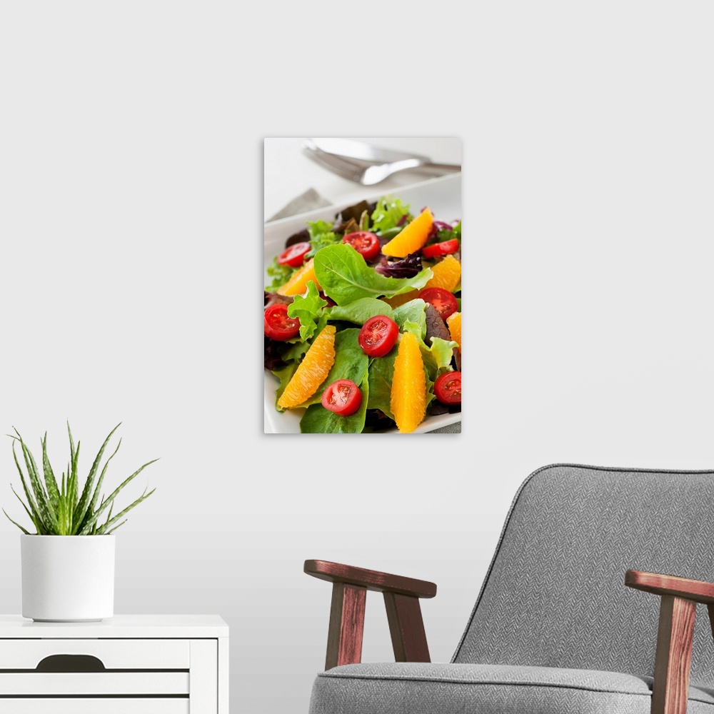 A modern room featuring Leafy greens topped with tomatoes and oranges is elegantly photographed.