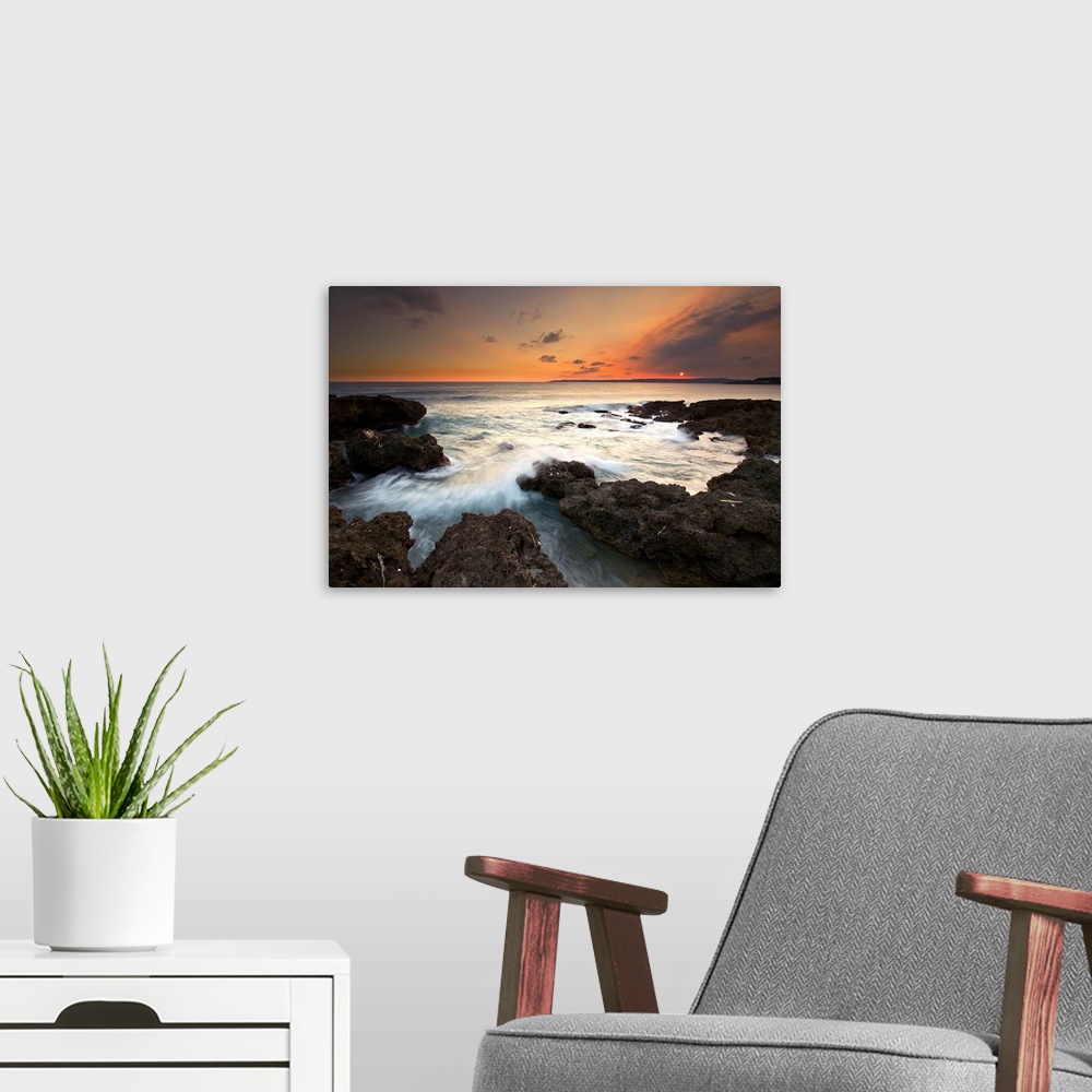 A modern room featuring Frog Rock, kenting at dusk with foaming waves rushing in and crashing on dark coral reefs while s...