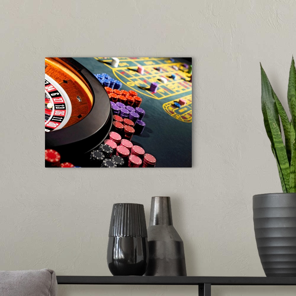 A modern room featuring Gambling chips stacked around roulette wheel on gaming table