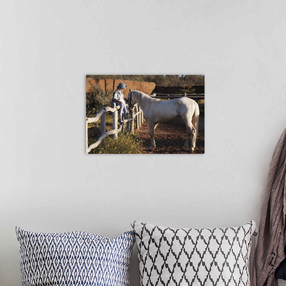 A bohemian room featuring Girl (6-7) sitting on fence, patting horse
