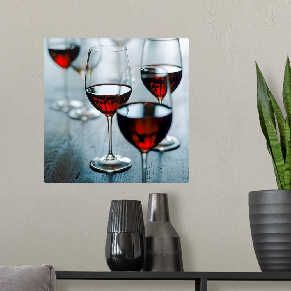 A modern room featuring Photograph of half full wine glasses on wooden table.