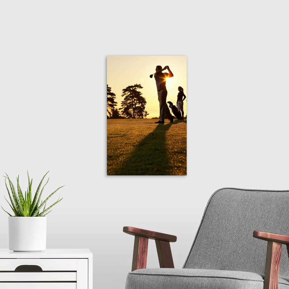 A modern room featuring Golfers playing golf at sunset, low angle view