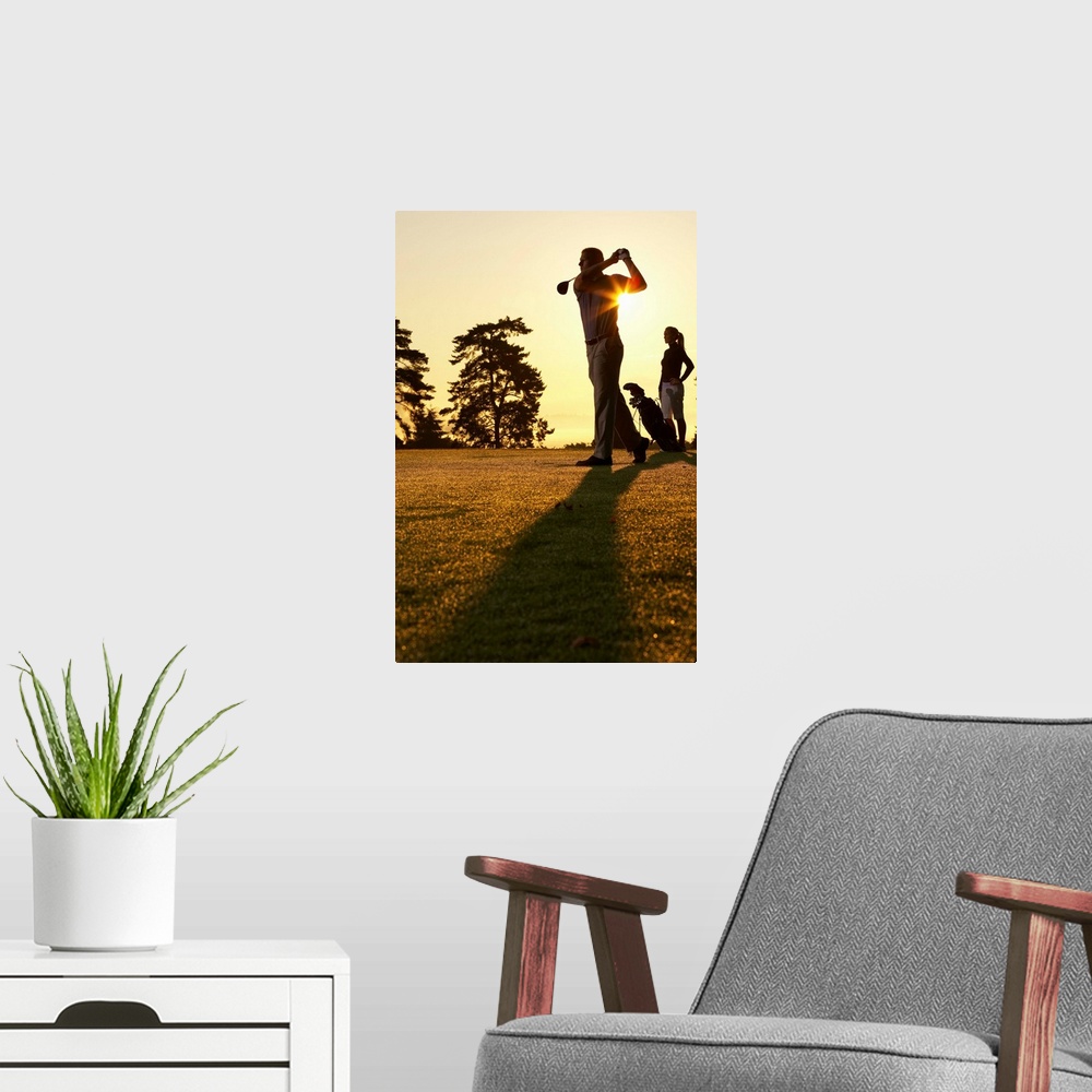 A modern room featuring Golfers playing golf at sunset, low angle view
