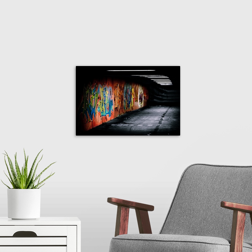 A modern room featuring Graffiti art painted in  under crossing. Graffitti is in color rest is black & white.