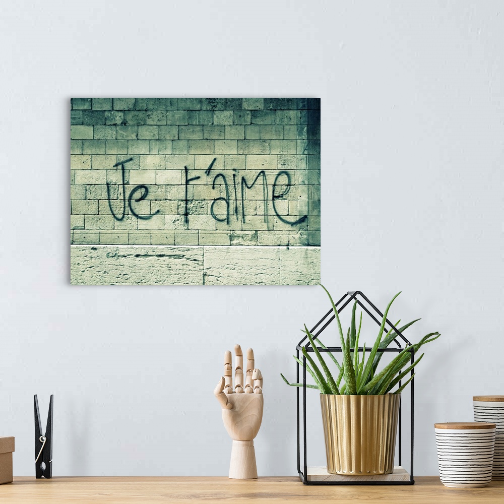 A bohemian room featuring Big canvas photo of a stone wall with the words "I love you" in French sprayed painted on it.