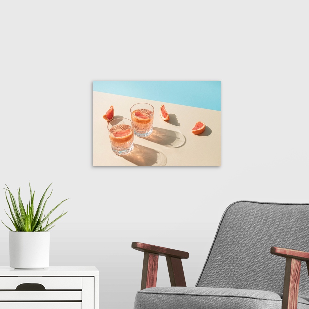 A modern room featuring Two drink glasses with slices of fresh grapefruit against a bright beige and blue background.