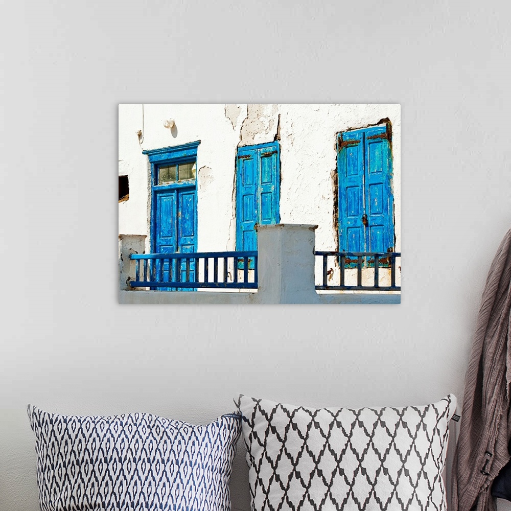 A bohemian room featuring Photograph of brightly-painted distressed doors against a stark, white wall on the Cycalades Isla...