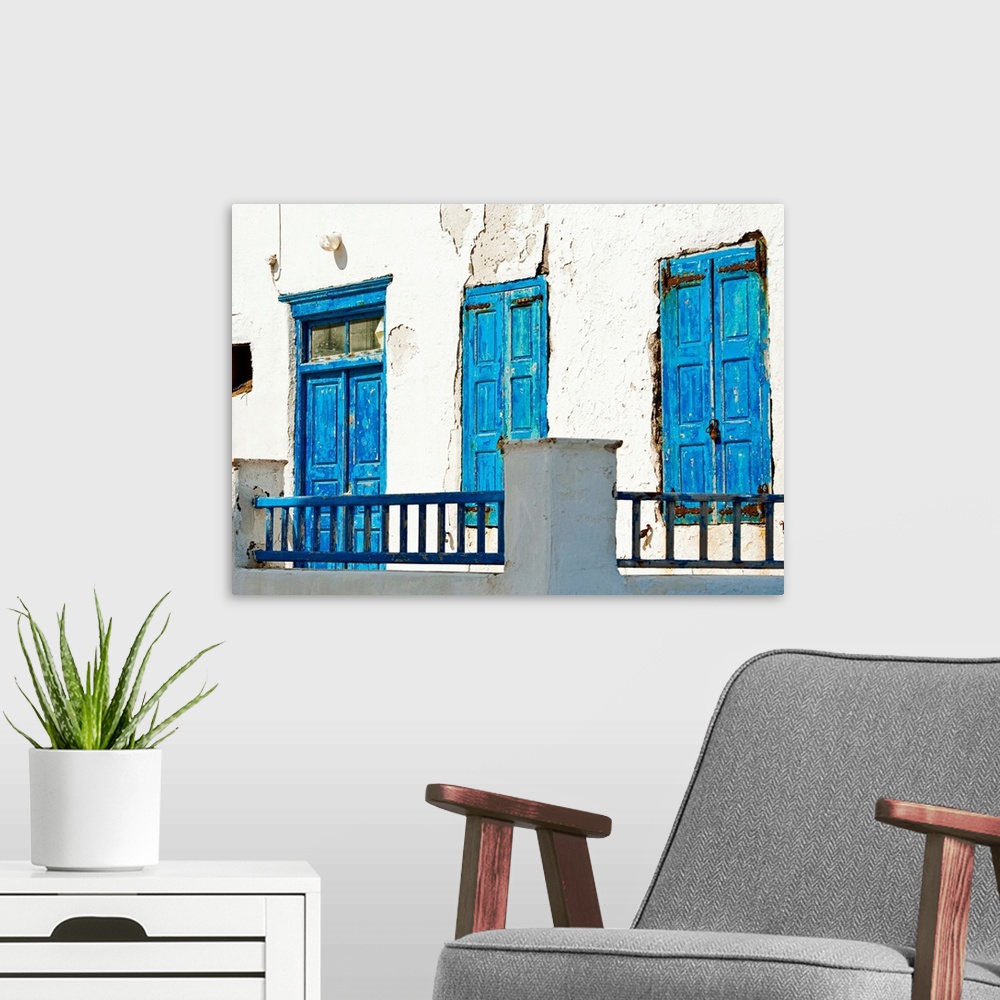 A modern room featuring Photograph of brightly-painted distressed doors against a stark, white wall on the Cycalades Isla...
