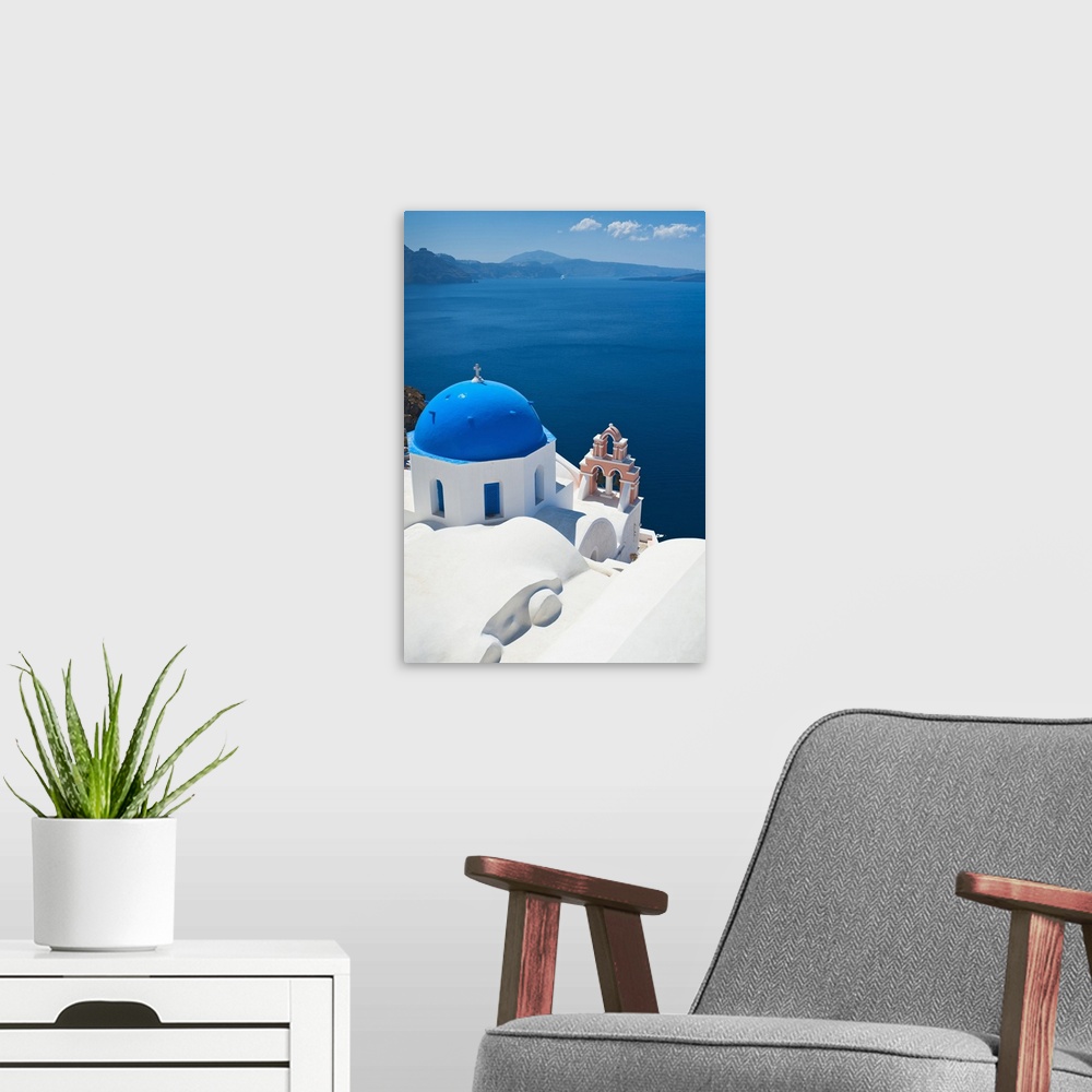 A modern room featuring Oversized, vertical, aerial photograph of the top of a church, overlooking blue waters over the c...
