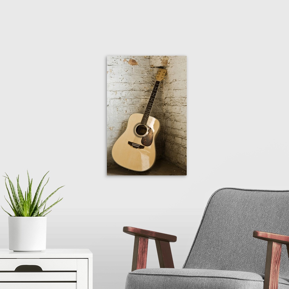A modern room featuring Large, portrait photograph of an acoustic guitar leaning in the corner of an old, rough, painted ...