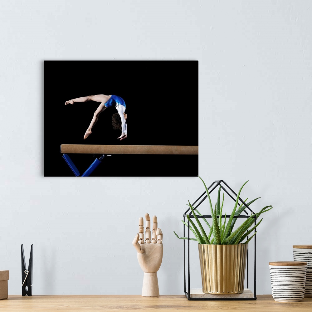 A bohemian room featuring Gymnast (9-10) flipping on balance beam, side view