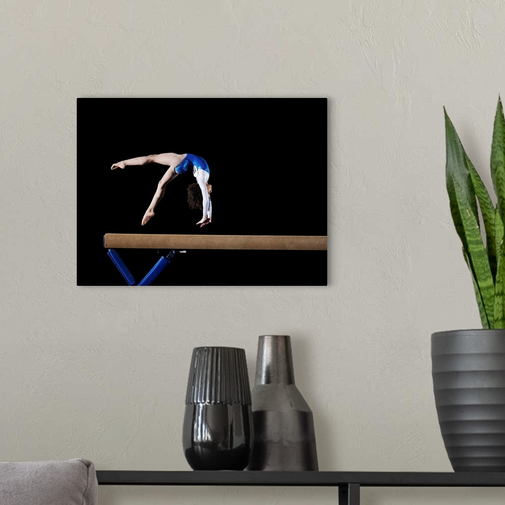 A modern room featuring Gymnast (9-10) flipping on balance beam, side view
