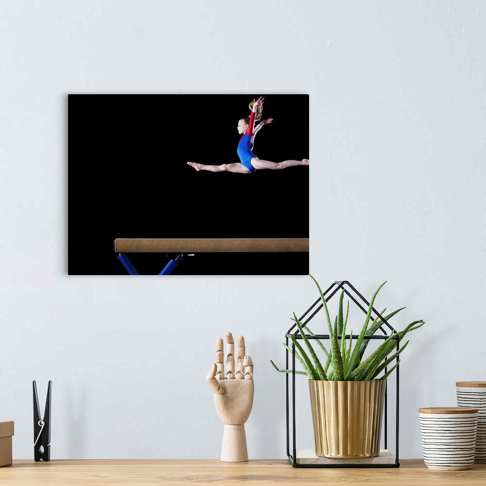 A bohemian room featuring Gymnast (9-10) leaping on balance beam