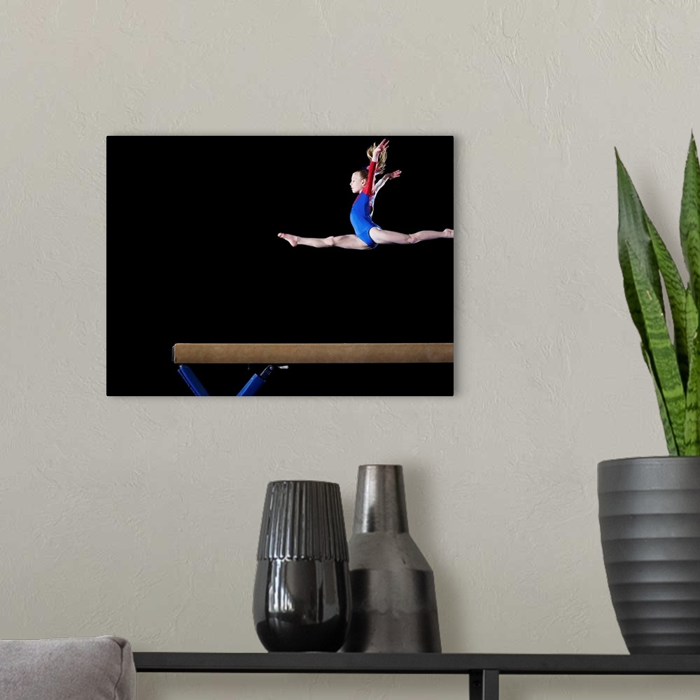 A modern room featuring Gymnast (9-10) leaping on balance beam