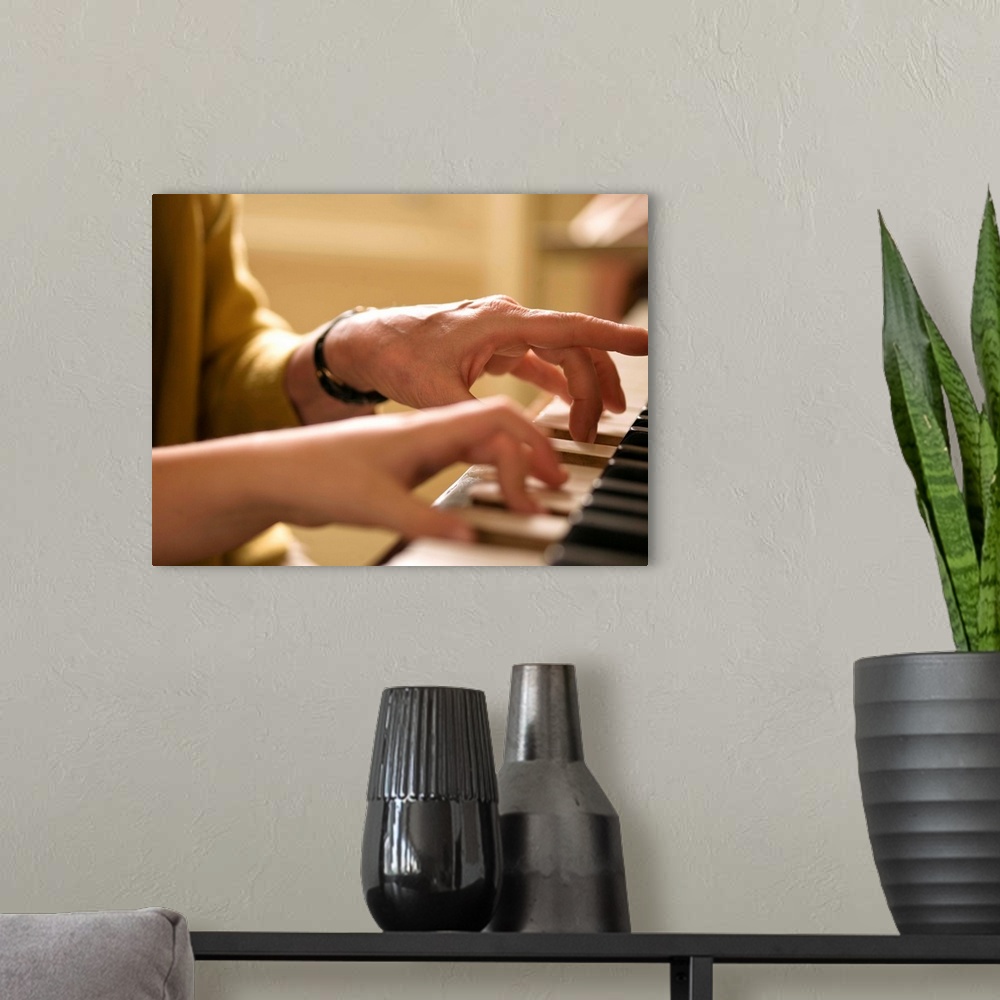 A modern room featuring Hands playing piano together