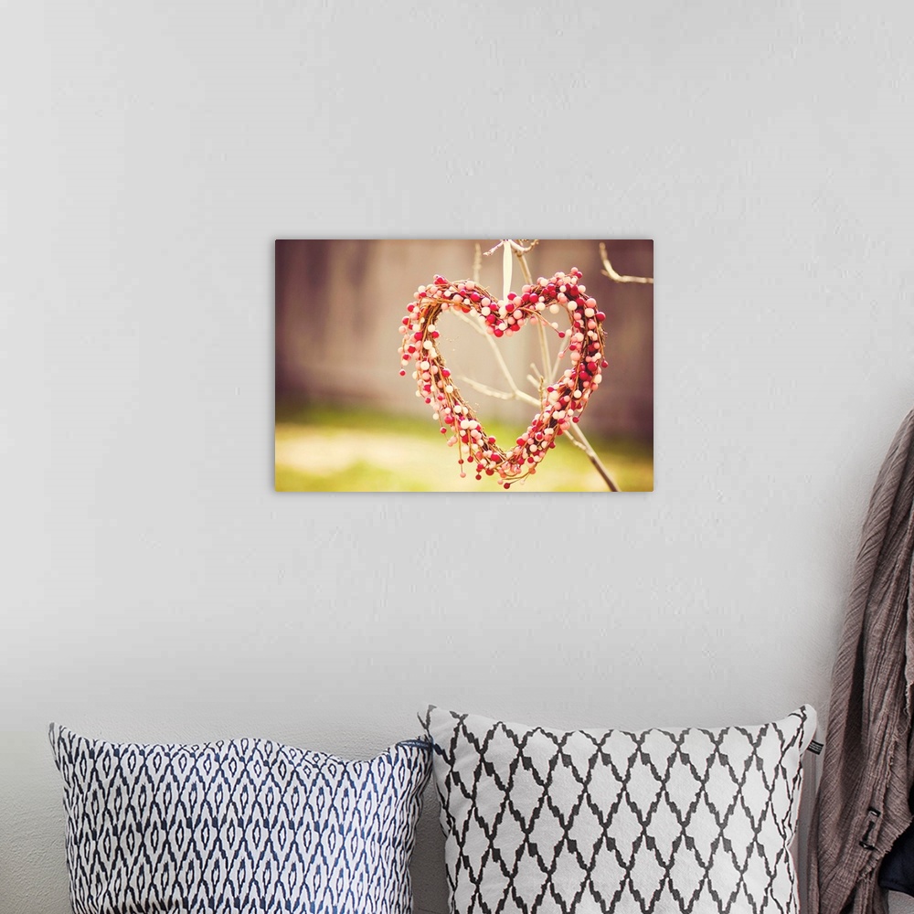 A bohemian room featuring Heart wreath made out of red, white and pink beads hanging on tree.