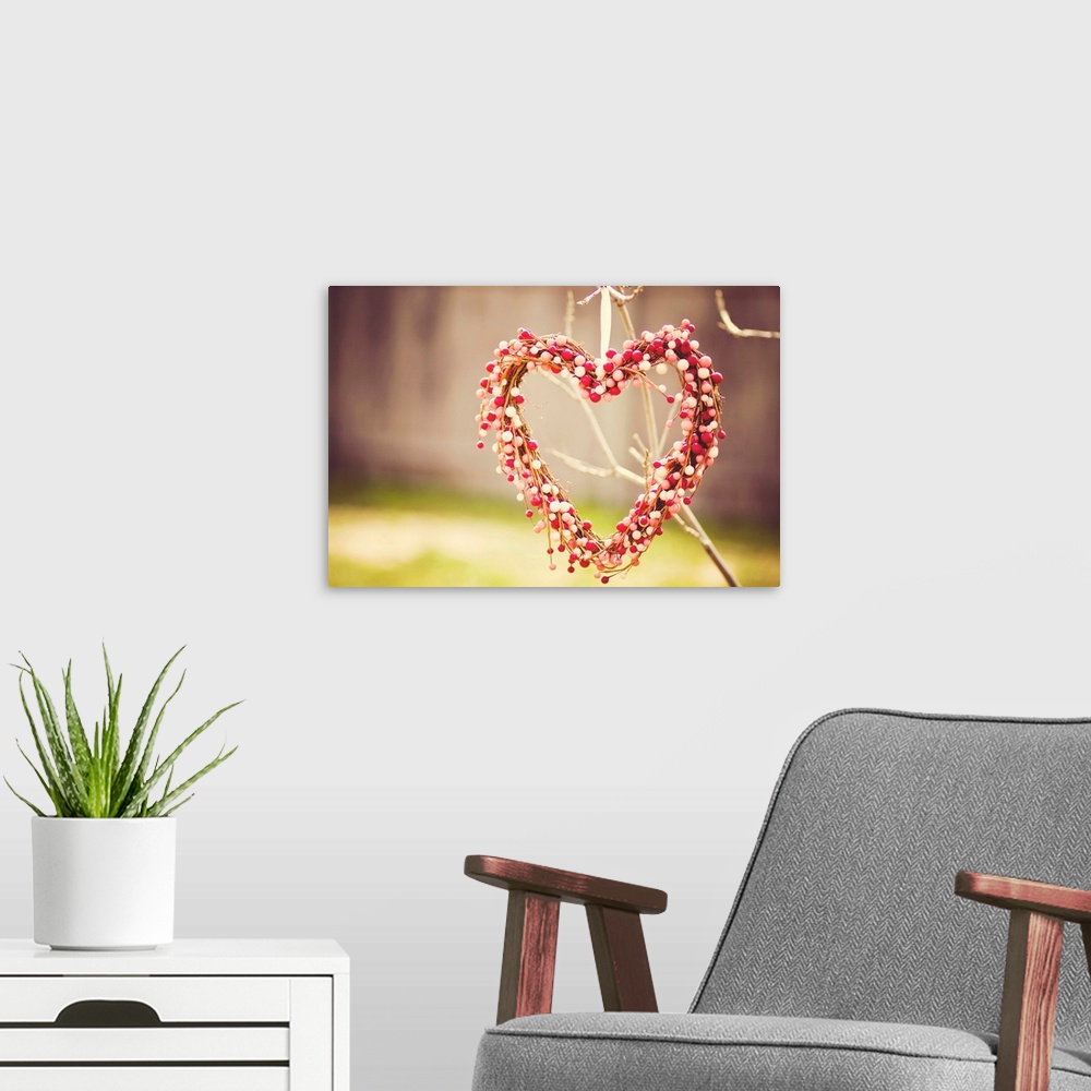 A modern room featuring Heart wreath made out of red, white and pink beads hanging on tree.