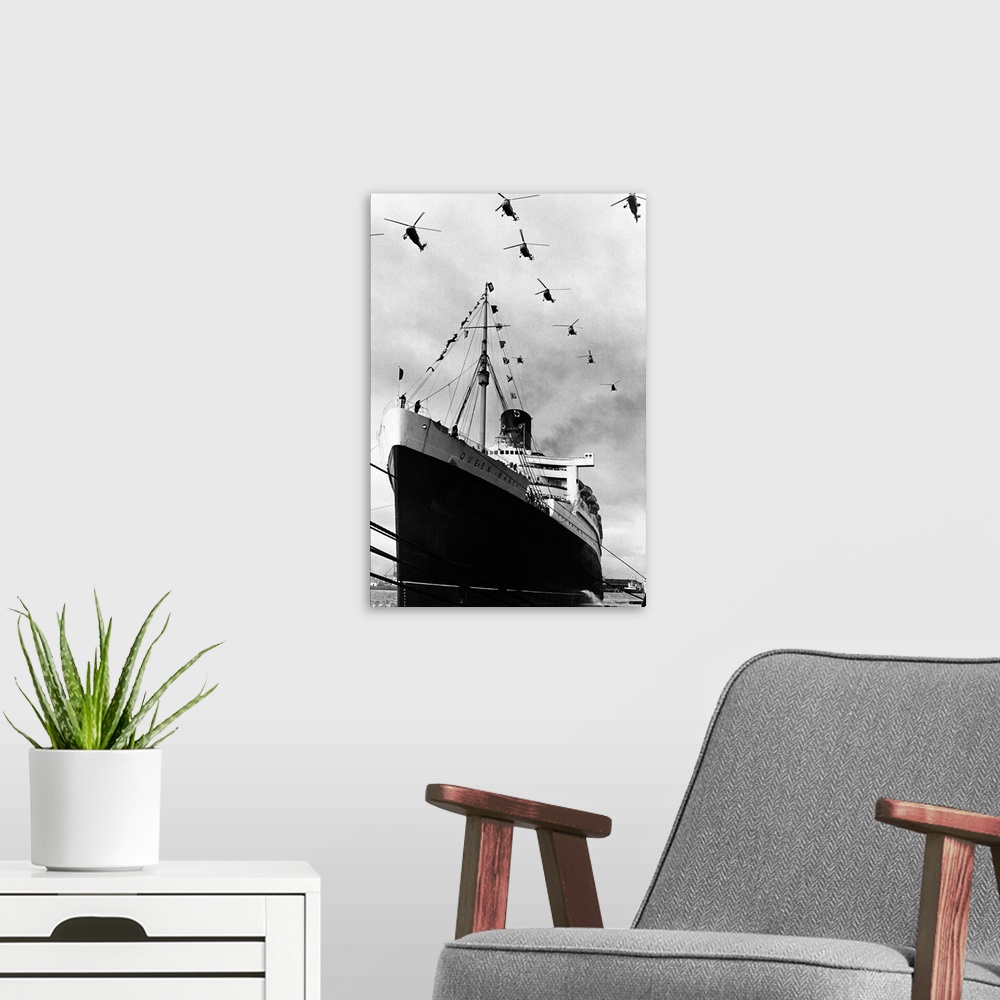 A modern room featuring Royal Navy helicopters fly in formation over the Cunard liner Queen Mary as she leaves Southampto...