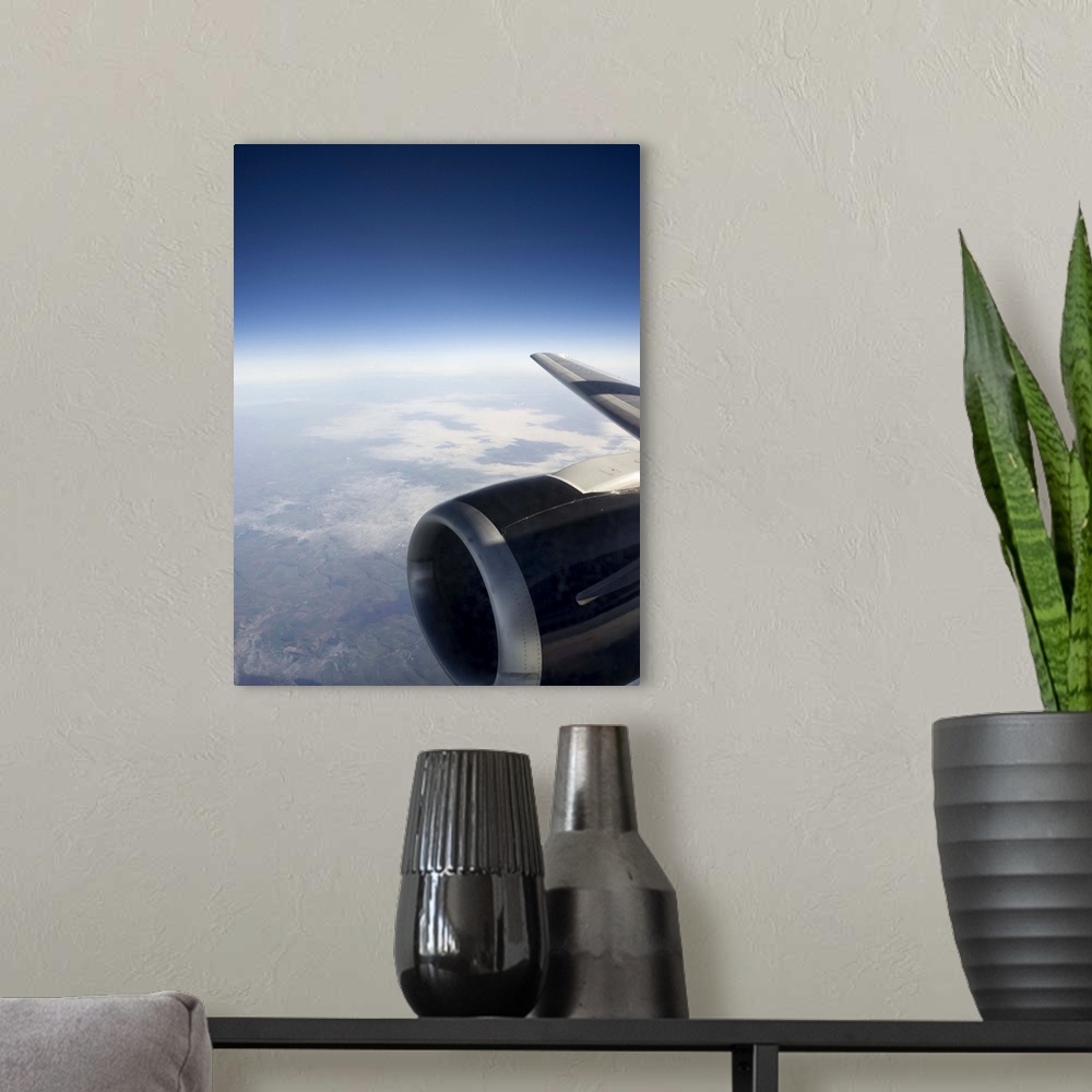 A modern room featuring High altitude view of a jet engine set against a gentle cloudscape with the outline of land and c...