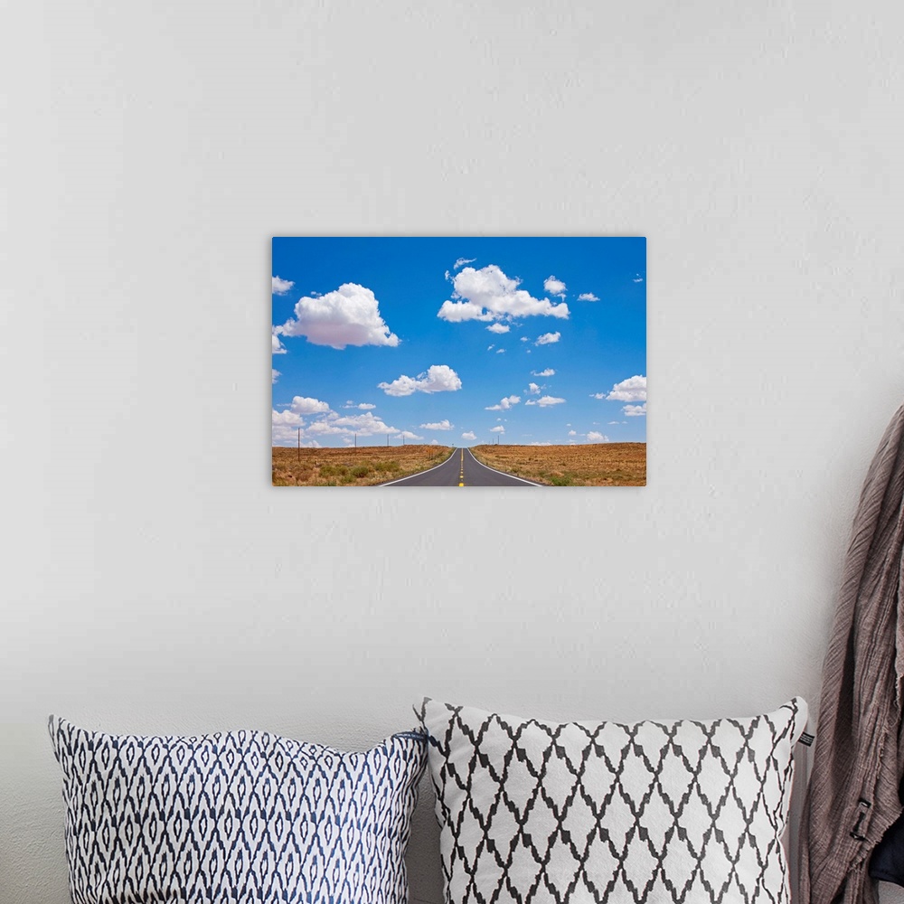 A bohemian room featuring Cumulus clouds above empty US 87 highway in desert on summer morning.