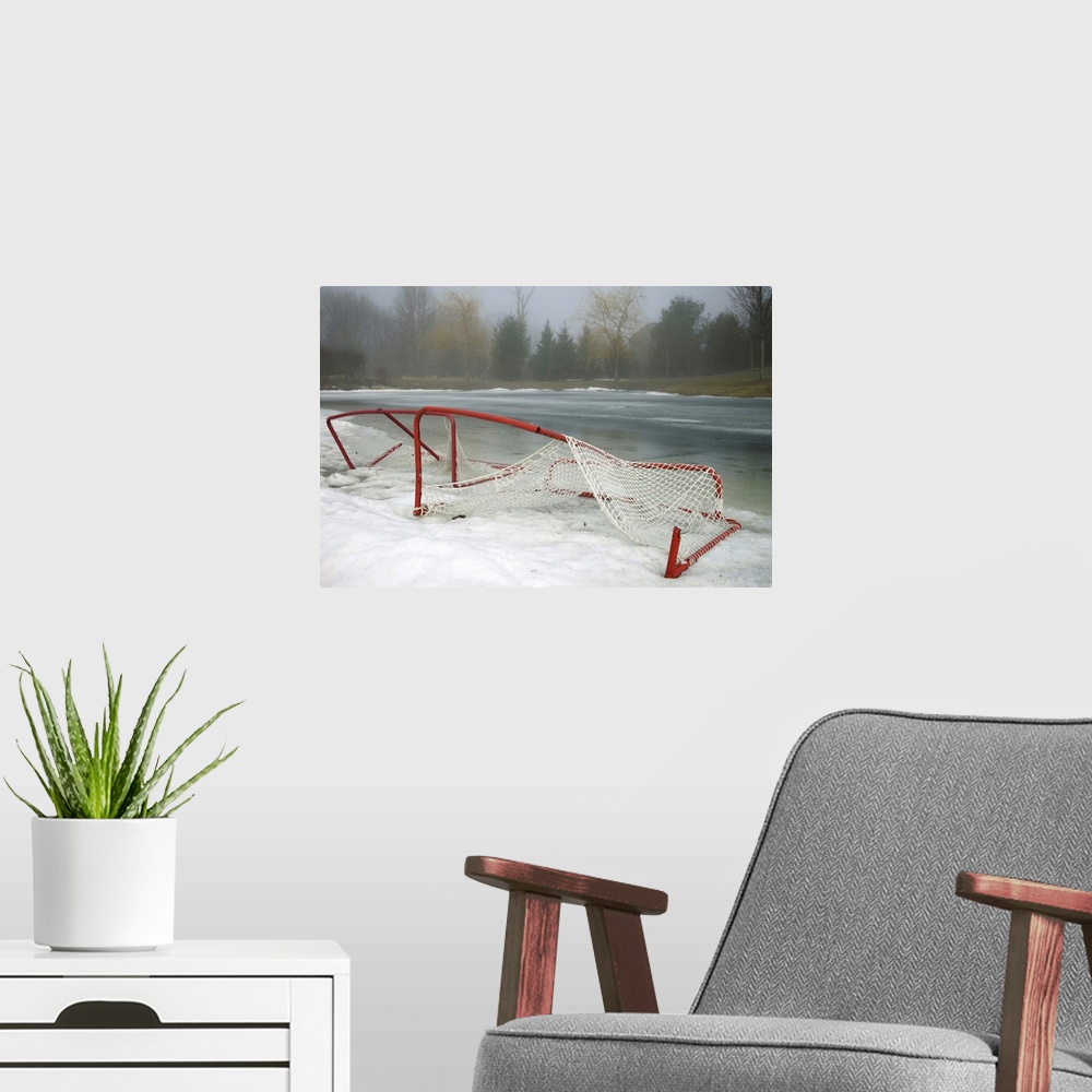 A modern room featuring Hockey net left from season in melting snow at Ottawa, Ontario, Canada.