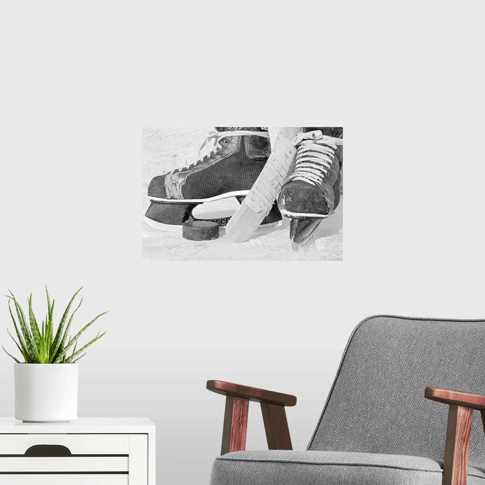 A modern room featuring Large, landscape photograph of vintage hockey skates on the ice.  Between the skates is the end o...