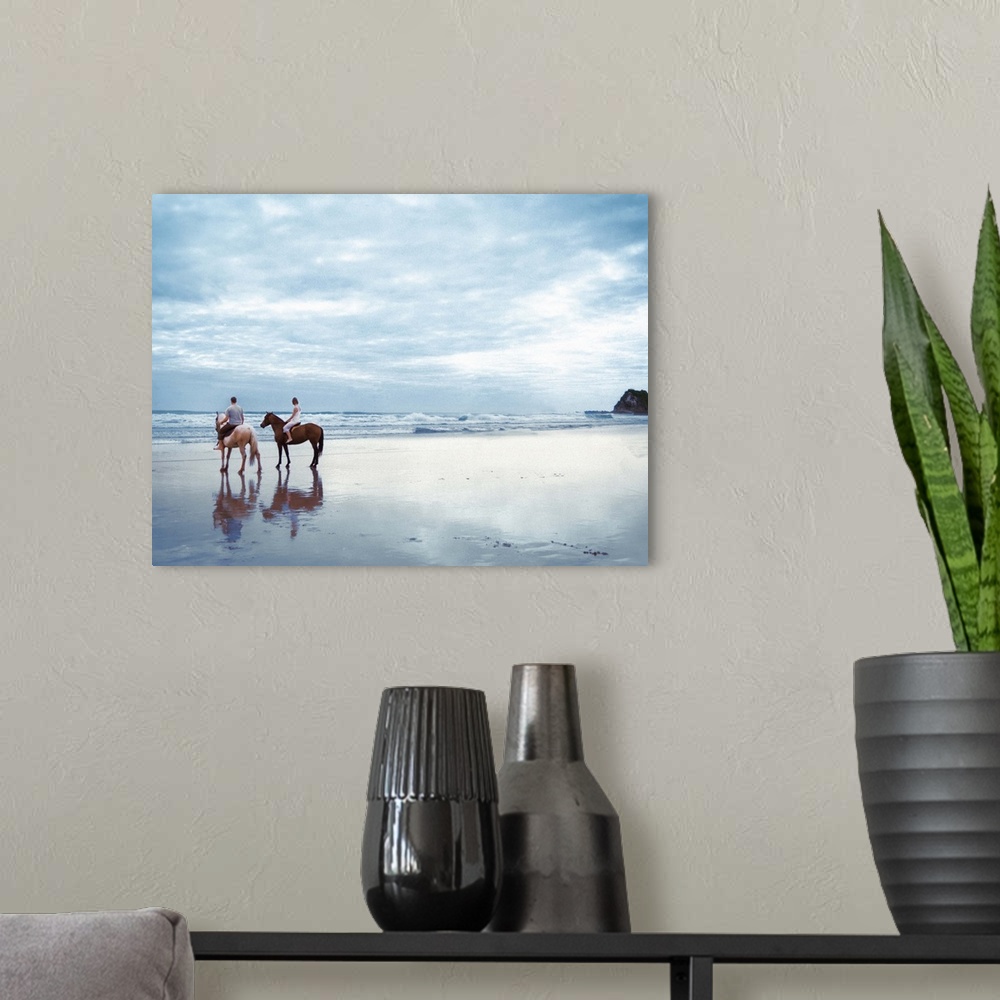 A modern room featuring A couple riding horses on Parkiri beach in New Zealand.