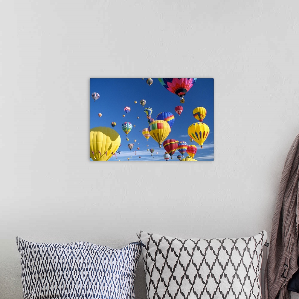 A bohemian room featuring Big, horizontal photograph of many brightly colored hot air balloons with varying patterns, float...