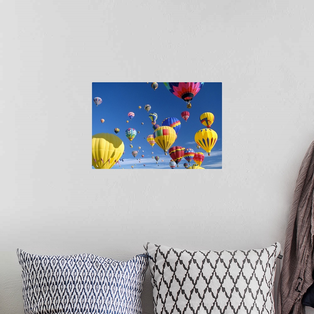 A bohemian room featuring Big, horizontal photograph of many brightly colored hot air balloons with varying patterns, float...