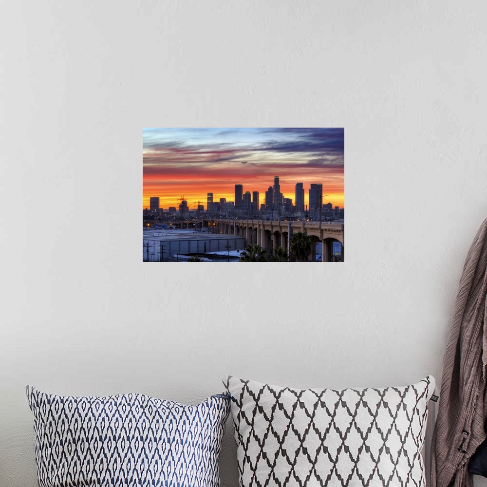 A bohemian room featuring Sunset creates a stunning display on the cloudy sky over a California cityscape with skyscrapers ...