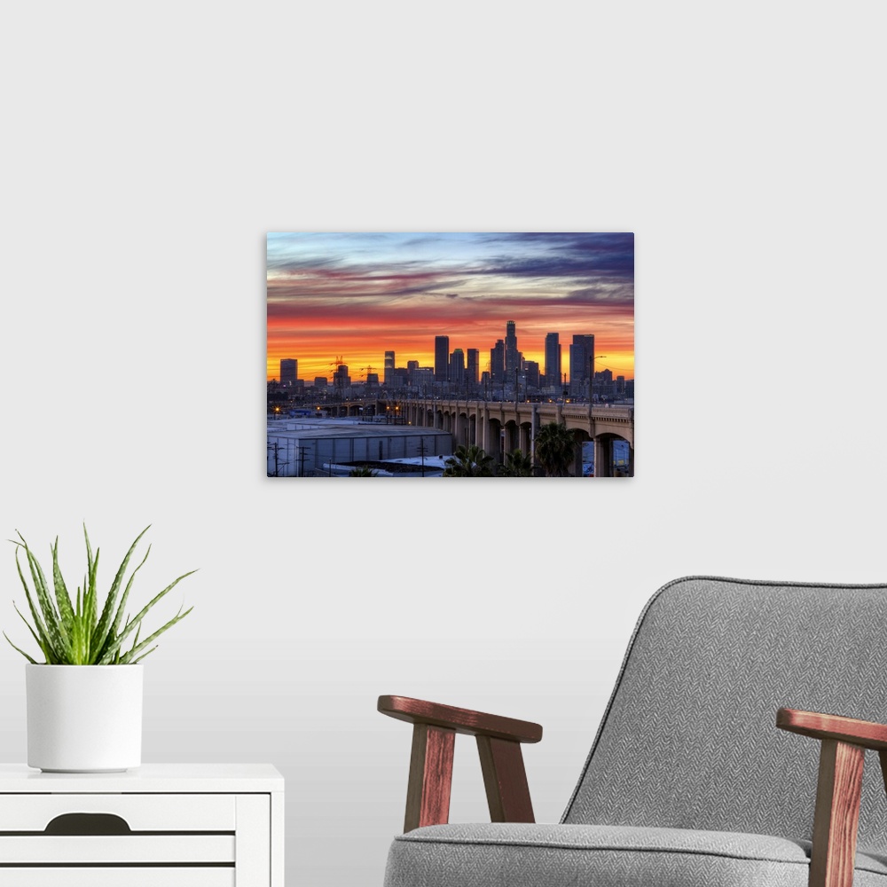 A modern room featuring Sunset creates a stunning display on the cloudy sky over a California cityscape with skyscrapers ...