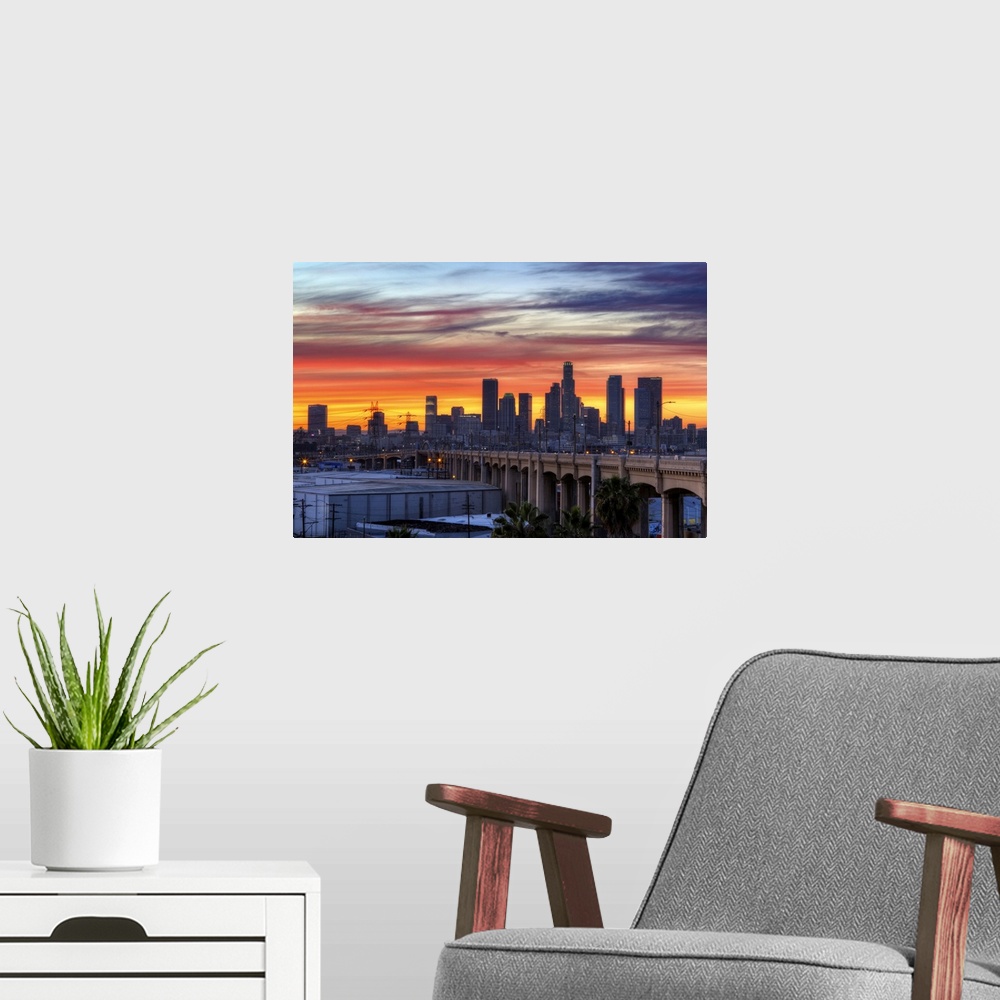 A modern room featuring Sunset creates a stunning display on the cloudy sky over a California cityscape with skyscrapers ...