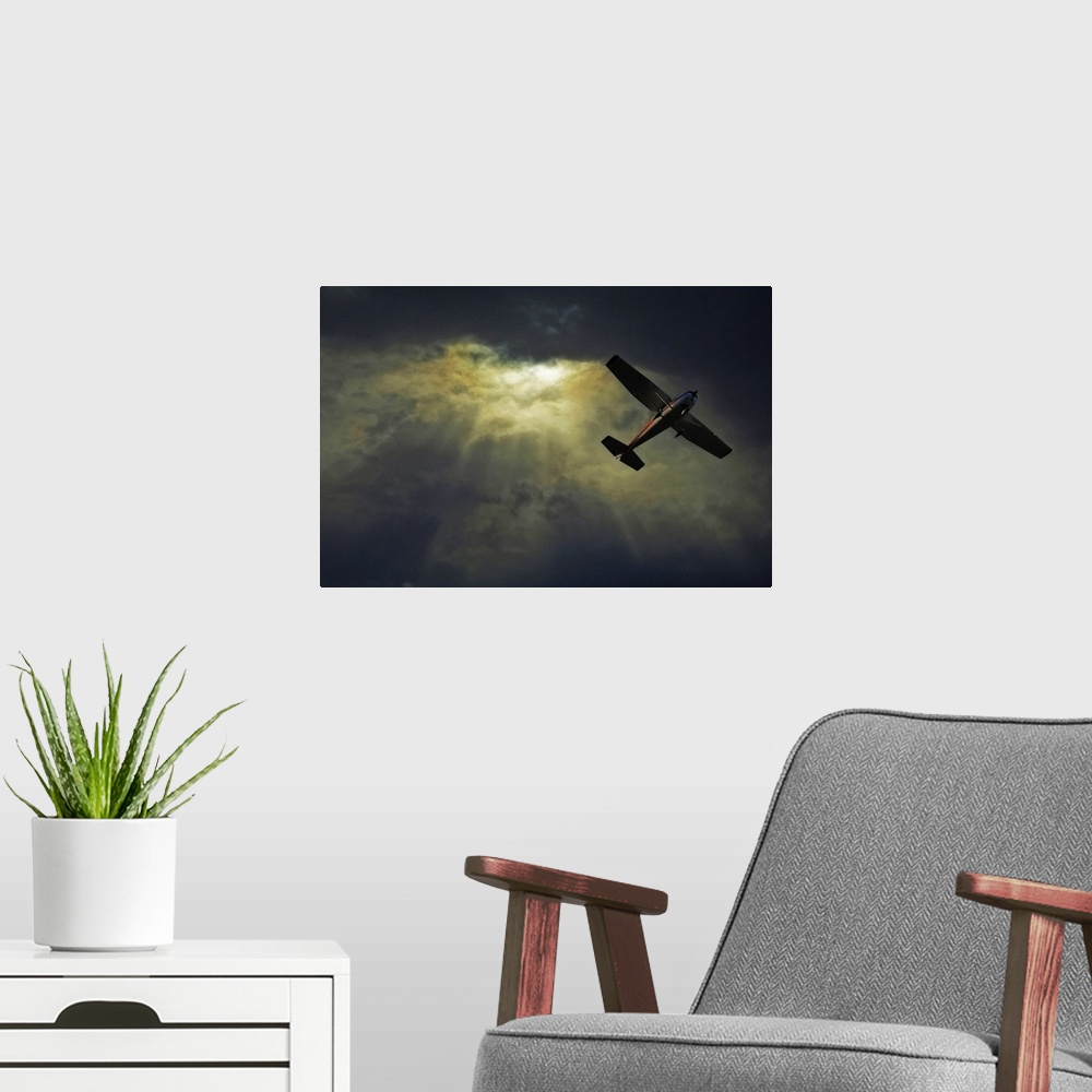A modern room featuring A photograph taken looking upward where rays of sunlight shine through dense cloud cover and a sm...