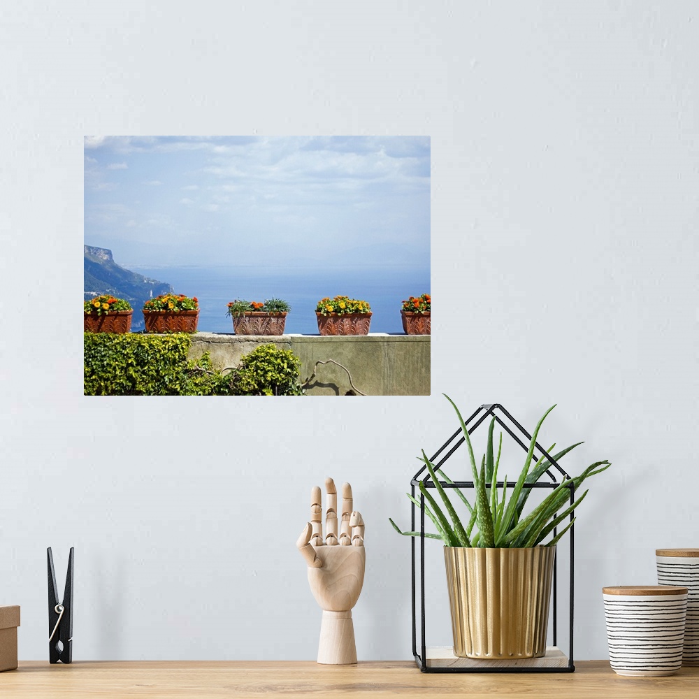 A bohemian room featuring Landscape, large photograph of numerous, rectangle flower pots with flowers, sitting on stone wal...