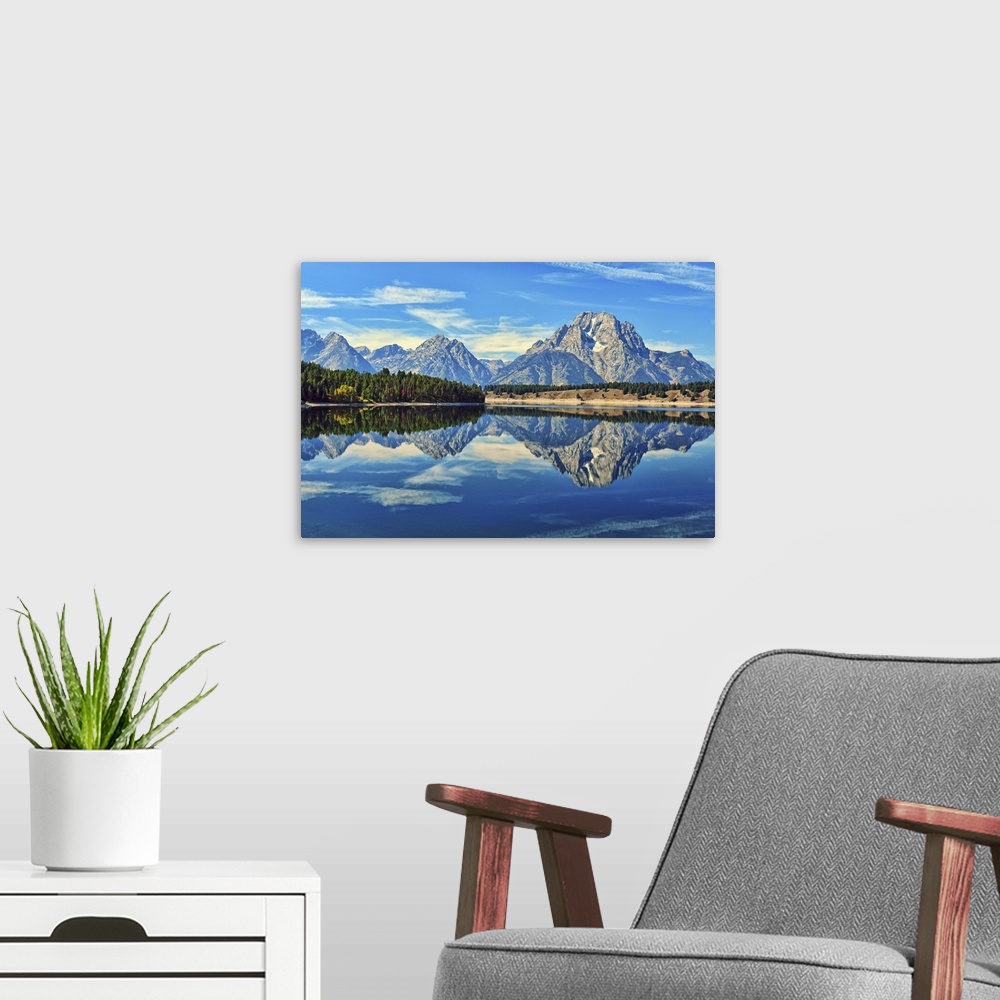 A modern room featuring A reflection of Mount Moran and the Teton mountain range in the still waters of Jackson Lake in G...