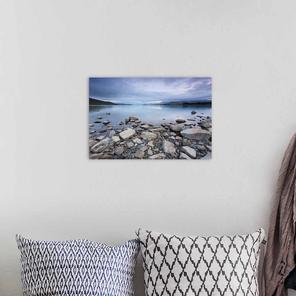A bohemian room featuring Lake Tekapo in New Zealand, with rocks in foreground during morning cloud.