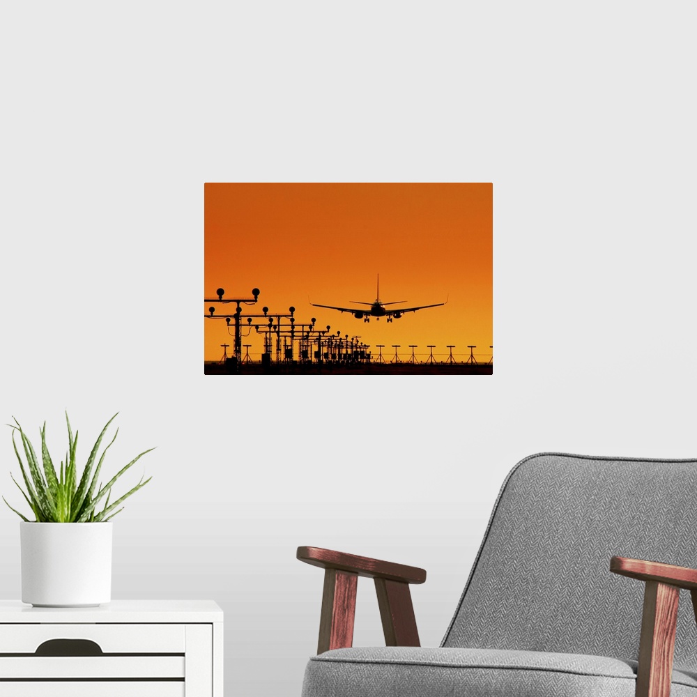A modern room featuring Landing of an airplane at sunset