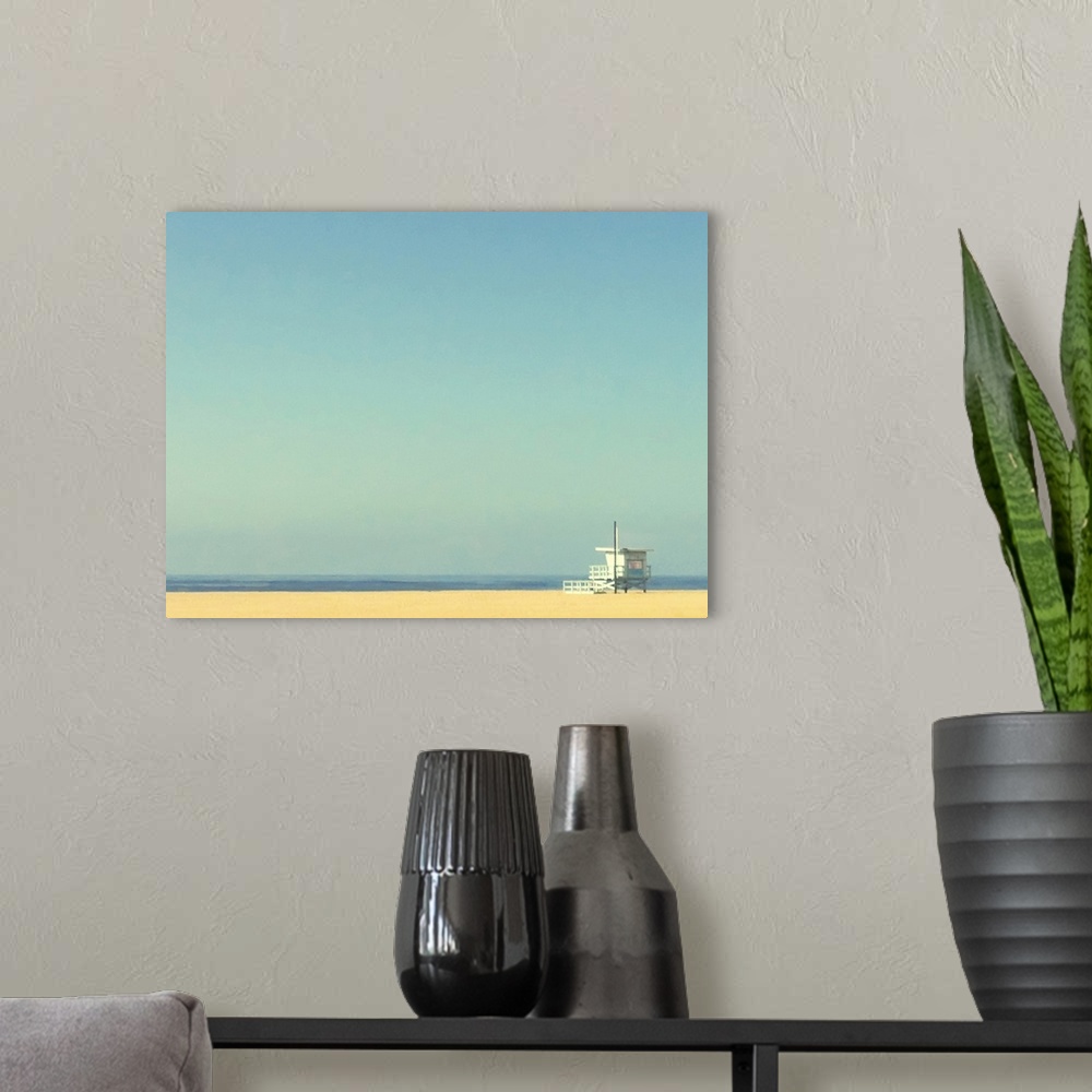 A modern room featuring Landscape, oversized photograph of a single lifeguard tower on an empty beach of golden sand, ben...