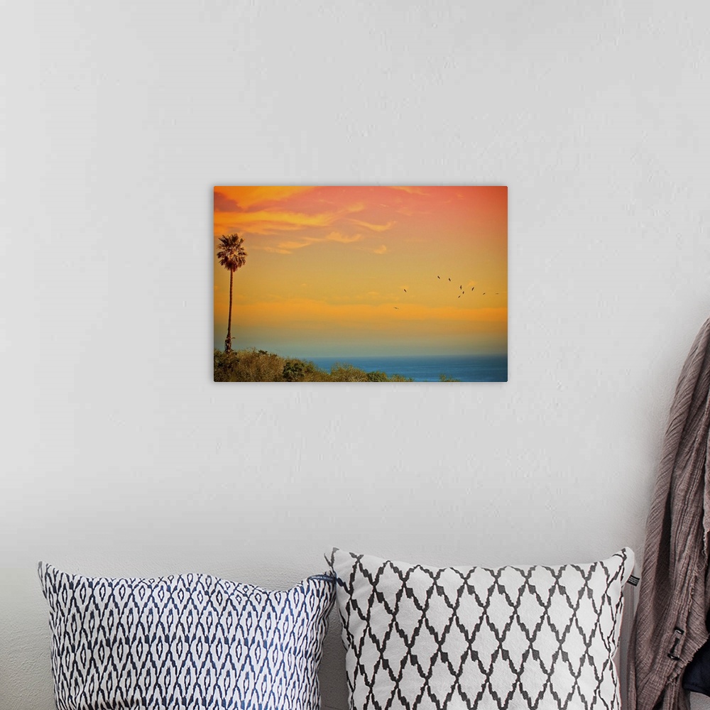 A bohemian room featuring Large canvas print of a beautifully colored sunset over the Pacific Ocean with a palm tree to the...
