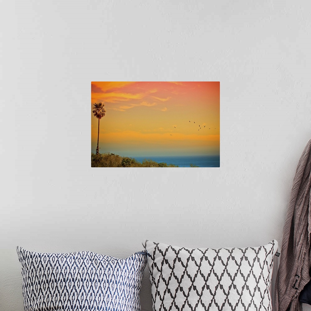 A bohemian room featuring Large canvas print of a beautifully colored sunset over the Pacific Ocean with a palm tree to the...