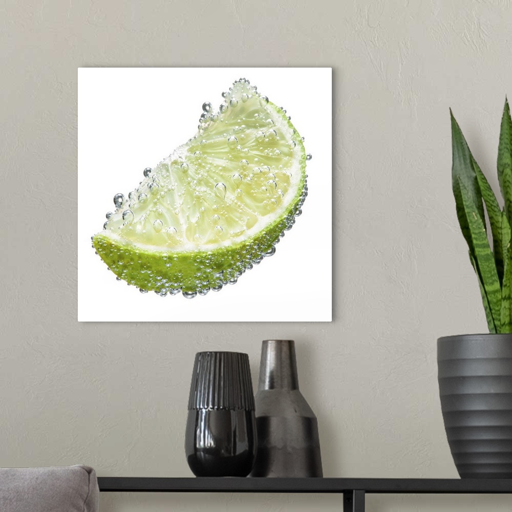 A modern room featuring A juicy ripe organic lime wedge fruit submerged in clean clear refreshing water and covered in bu...