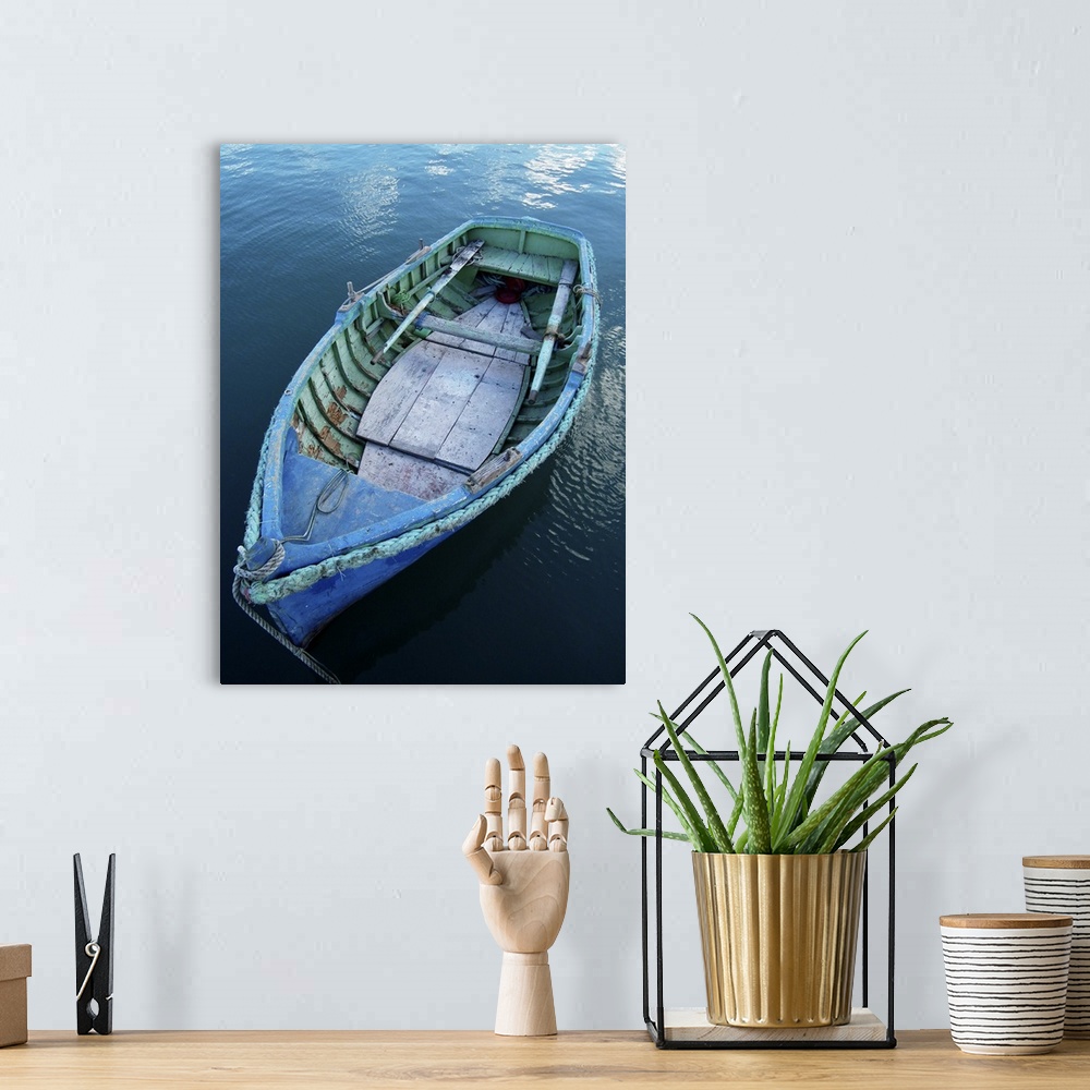 A bohemian room featuring Rustic wooden fishing boat moored in calm waters in fishing village of Marsaxlokk, Malta.
