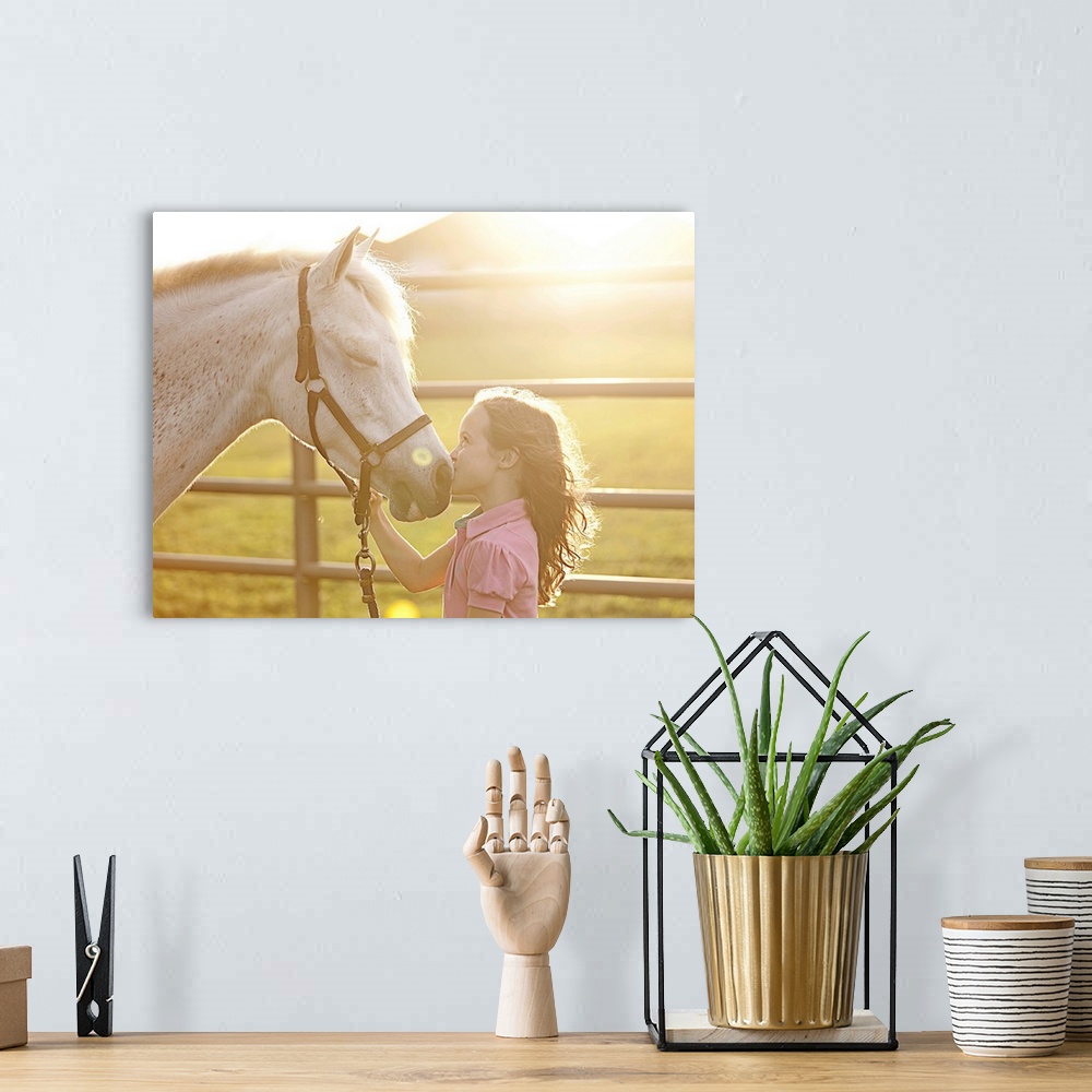 A bohemian room featuring A little girl at sunset kissing her horse on the nose, while horse has its eyes closed
