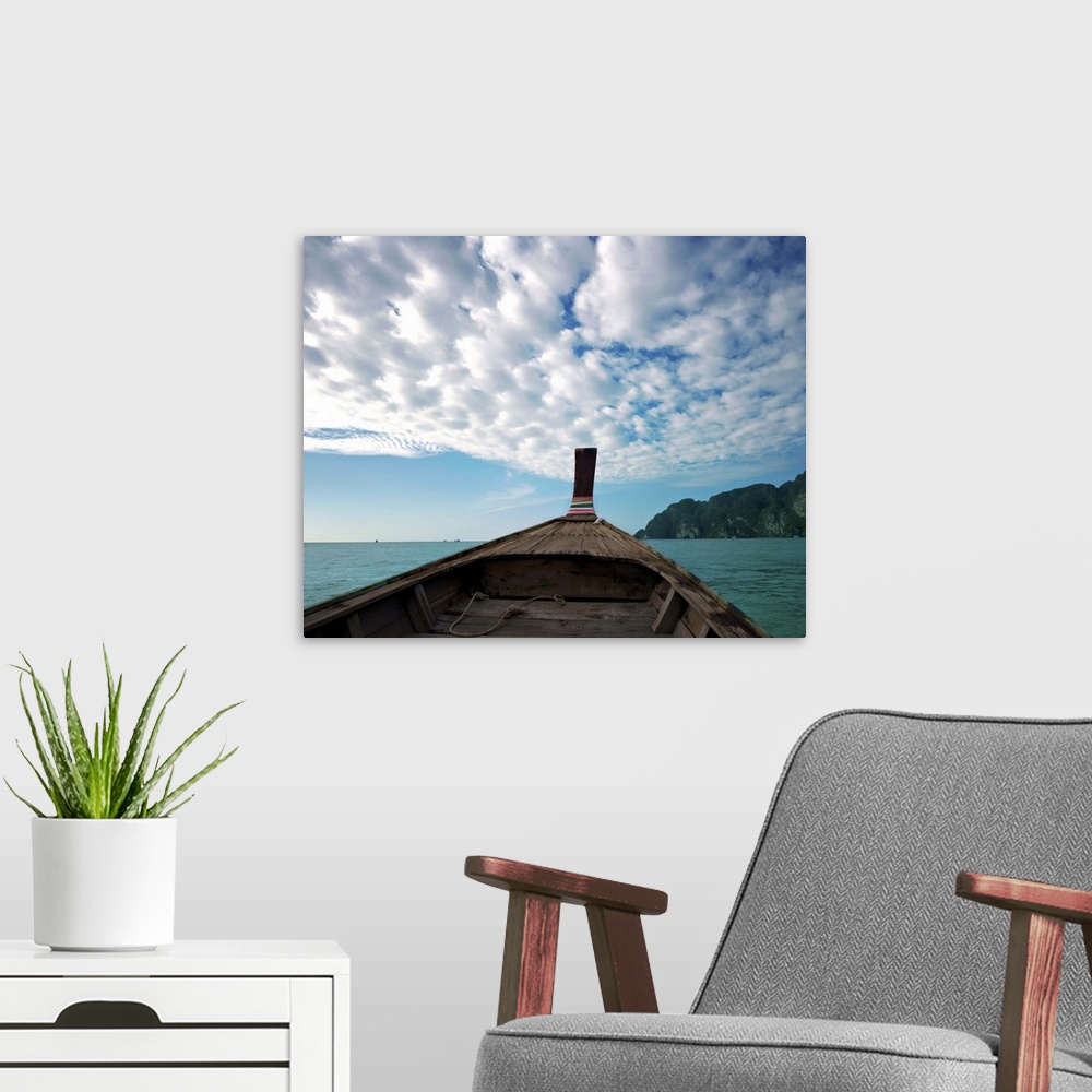 A modern room featuring Long boat in sea with cloudy sky and mountain in background.