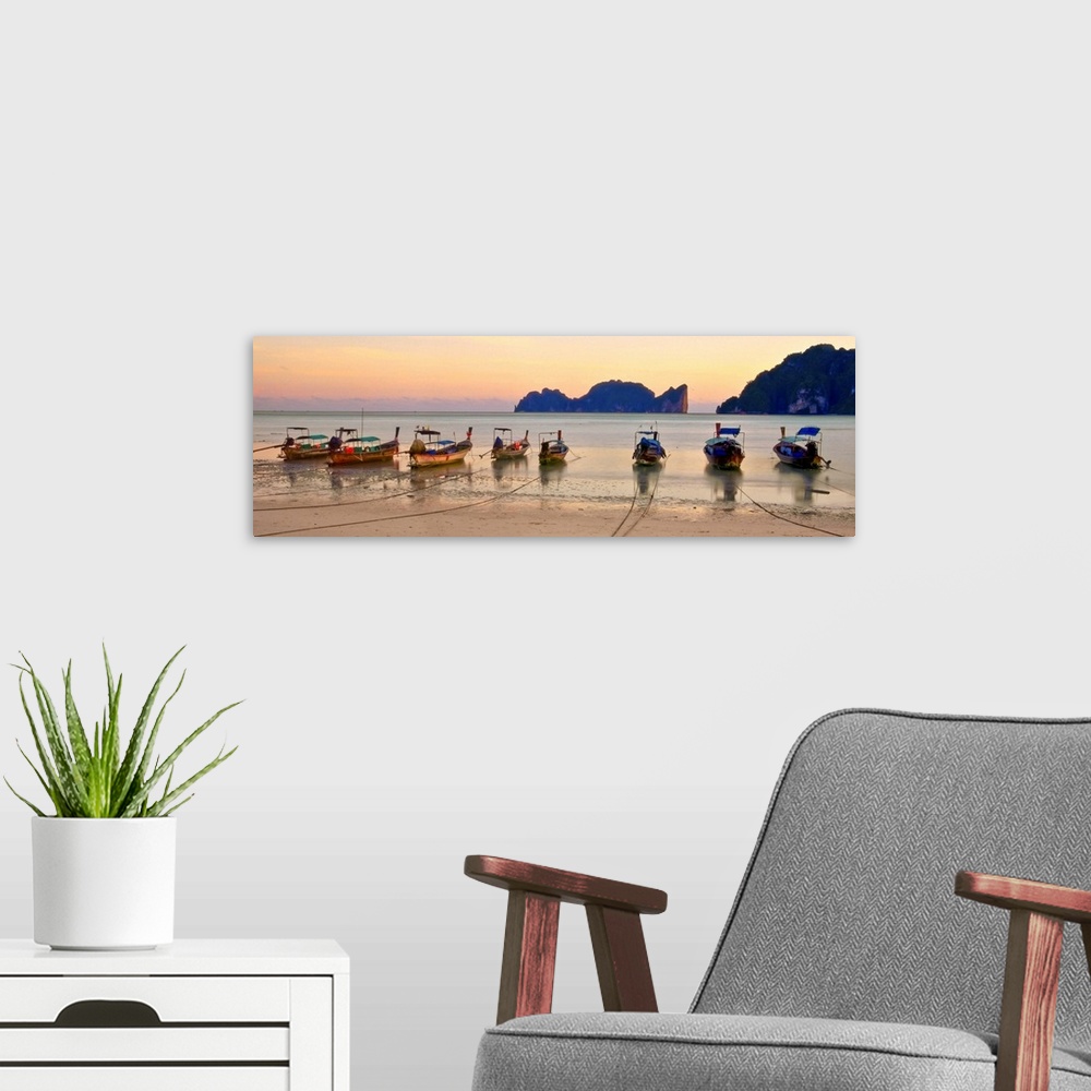 A modern room featuring Long tail boats on beach at sunset.
