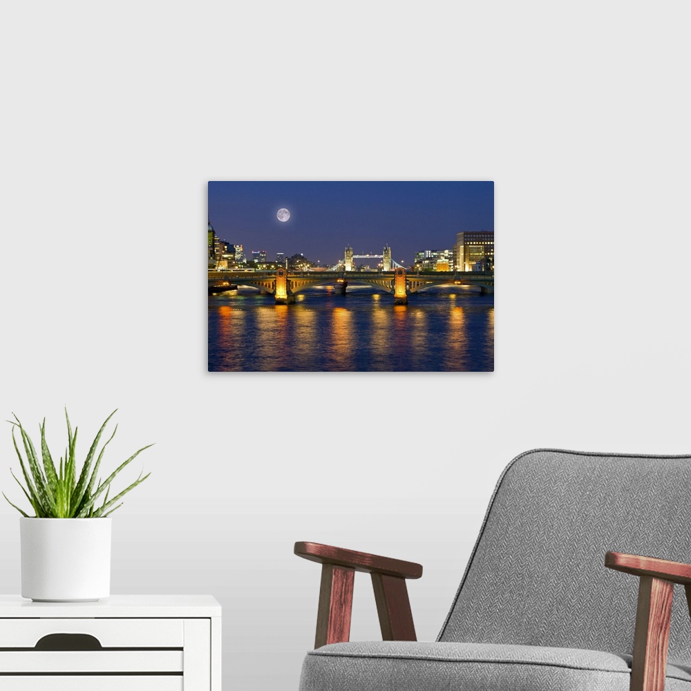 A modern room featuring Horizontal photograph on a giant wall hanging of the Millennium Footbridge, lit at night over the...