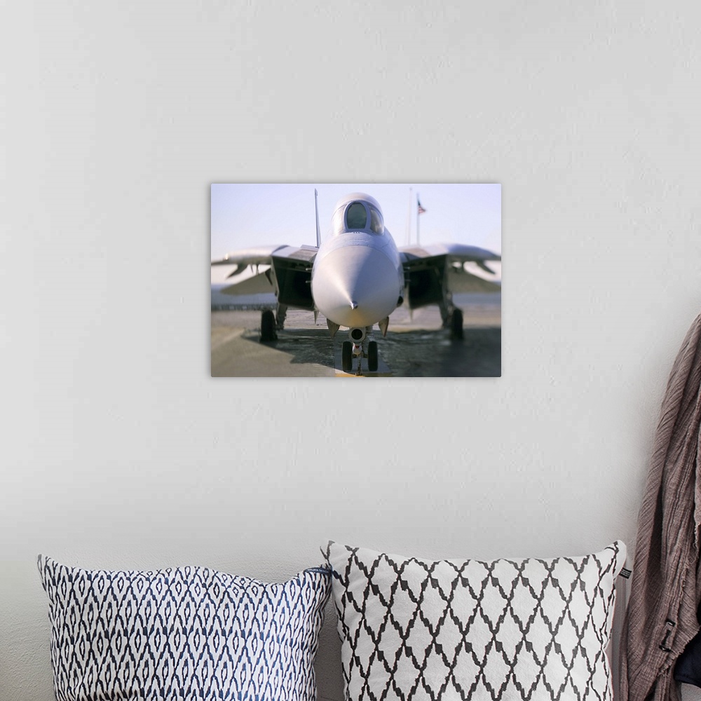 A bohemian room featuring Looking straight on at the nose of an F-14 military aircraft at the airport.