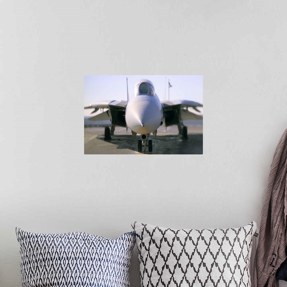 A bohemian room featuring Looking straight on at the nose of an F-14 military aircraft at the airport.